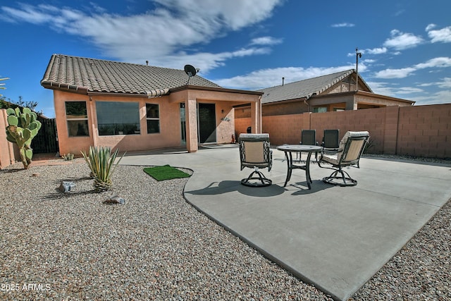 rear view of house with a patio area, stucco siding, a tile roof, and a fenced backyard