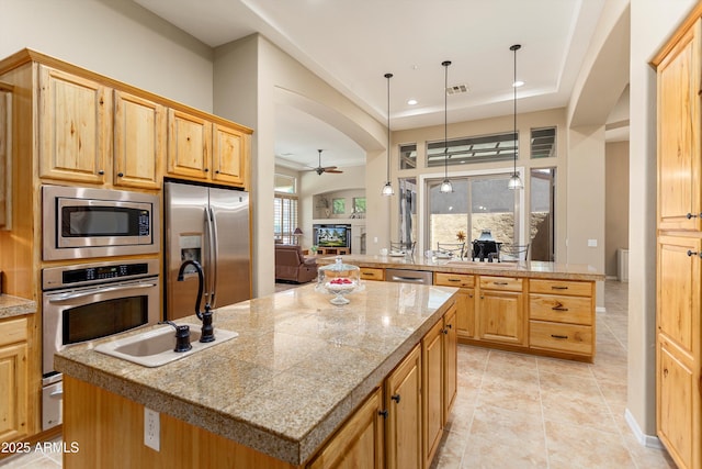 12976 W Plum Rd, Peoria, AZ 85383 - kitchen featuring arched walkways, a sink, stainless steel appliances, and a center island with sink