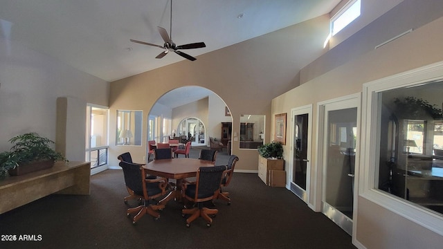 dining space with high vaulted ceiling, ceiling fan, and dark colored carpet