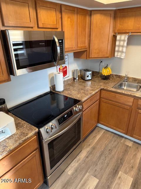 kitchen featuring appliances with stainless steel finishes, light hardwood / wood-style floors, and sink