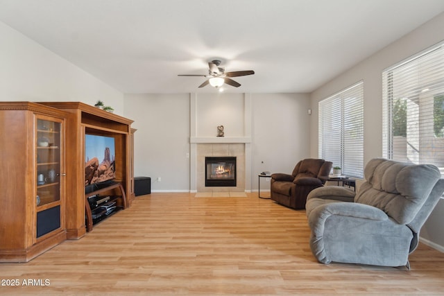 living room with ceiling fan, light hardwood / wood-style floors, and a tile fireplace