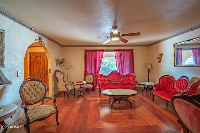 living room with crown molding, ceiling fan, and a textured ceiling