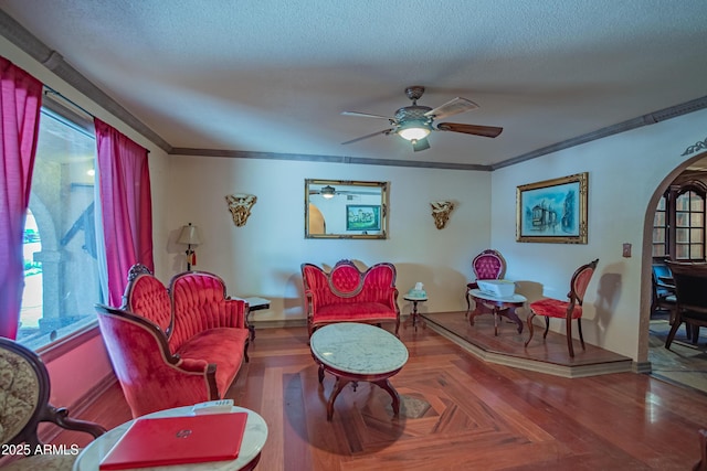 living room featuring ceiling fan, parquet flooring, ornamental molding, and a textured ceiling