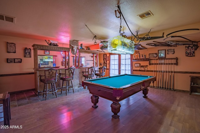 playroom with hardwood / wood-style flooring, pool table, bar area, and a textured ceiling