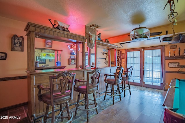 bar with french doors and a textured ceiling