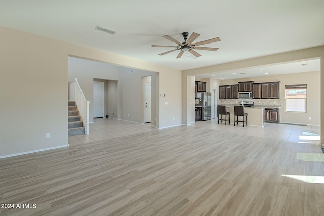 unfurnished living room featuring ceiling fan and light hardwood / wood-style floors