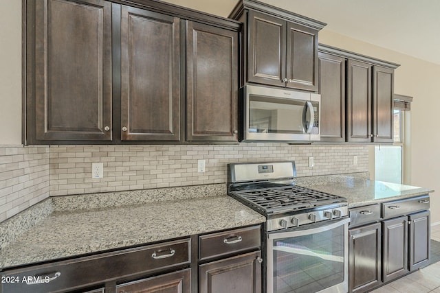 kitchen with decorative backsplash, appliances with stainless steel finishes, dark brown cabinetry, and light stone countertops