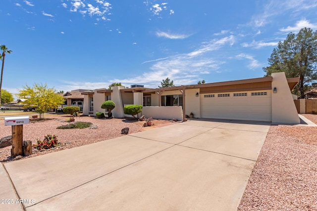 pueblo-style house featuring a garage, stucco siding, and concrete driveway
