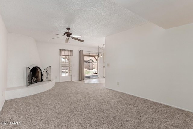 unfurnished living room featuring a textured ceiling, carpet, a large fireplace, and ceiling fan with notable chandelier