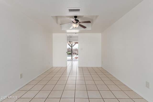 spare room with a tray ceiling, visible vents, light tile patterned floors, and ceiling fan with notable chandelier