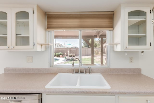kitchen with a sink, light countertops, white cabinets, and dishwasher
