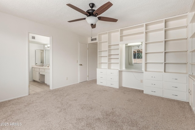 unfurnished bedroom featuring baseboards, light carpet, a textured ceiling, and visible vents