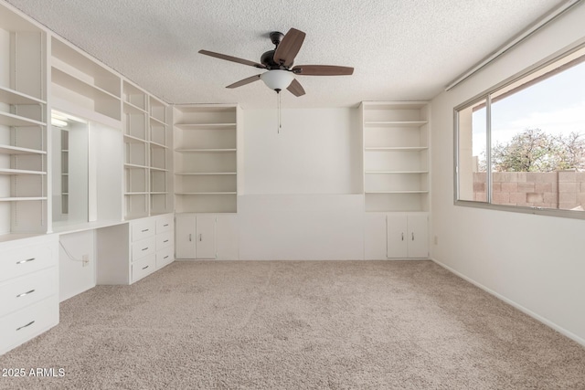 unfurnished bedroom featuring carpet floors, a ceiling fan, a textured ceiling, and built in study area