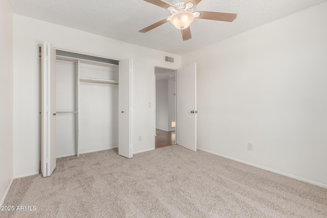 unfurnished bedroom featuring visible vents, carpet floors, a closet, baseboards, and ceiling fan