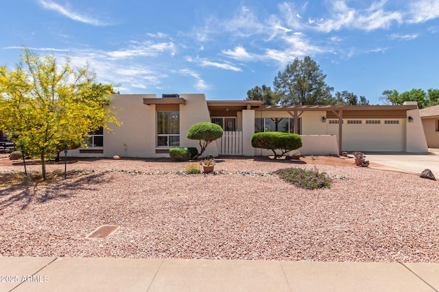 pueblo-style home featuring a garage, stucco siding, and concrete driveway