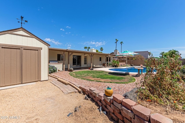 back of house featuring a fenced in pool, a storage unit, a patio, and a fenced backyard