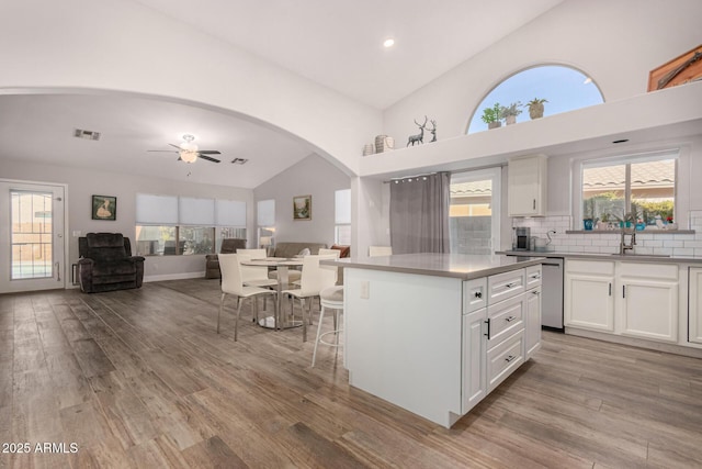 kitchen featuring ceiling fan, a center island, decorative backsplash, white cabinetry, and light wood-type flooring