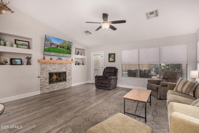 living room with hardwood / wood-style flooring, ceiling fan, a fireplace, built in features, and vaulted ceiling