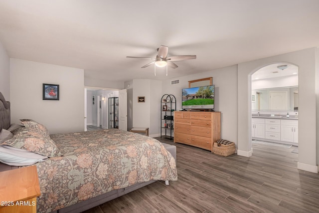 bedroom with ceiling fan, dark hardwood / wood-style flooring, and connected bathroom