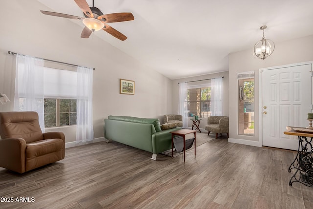 living room featuring ceiling fan with notable chandelier, hardwood / wood-style floors, and vaulted ceiling