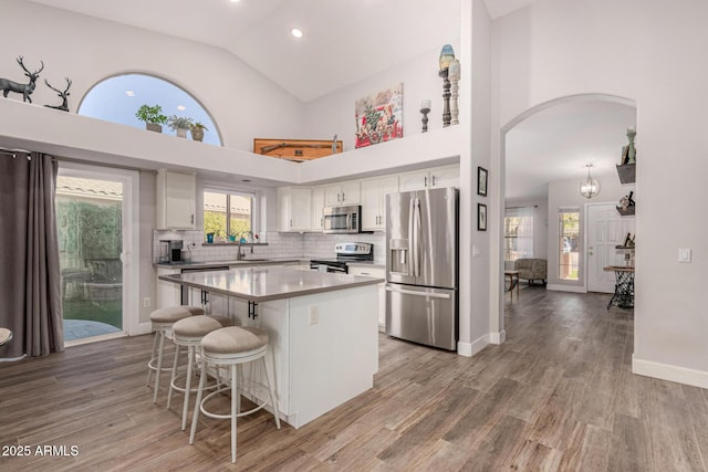 kitchen with a kitchen island, sink, appliances with stainless steel finishes, a kitchen breakfast bar, and white cabinets