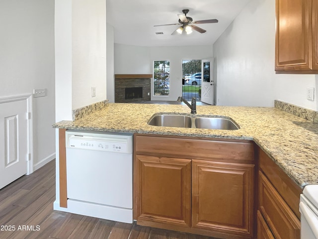 kitchen featuring kitchen peninsula, ceiling fan, sink, dishwasher, and a stone fireplace