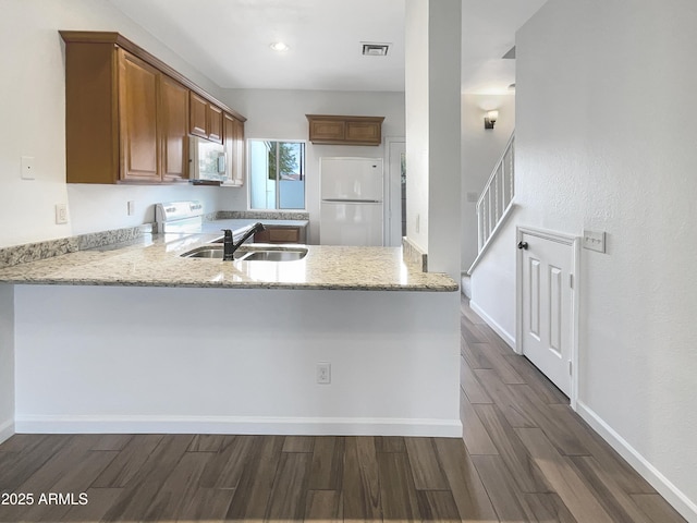 kitchen featuring sink, light stone counters, white appliances, and kitchen peninsula