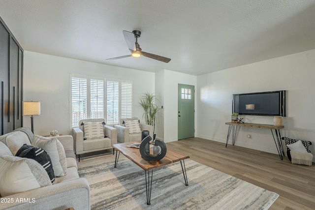 living room featuring ceiling fan, a textured ceiling, and light wood-type flooring