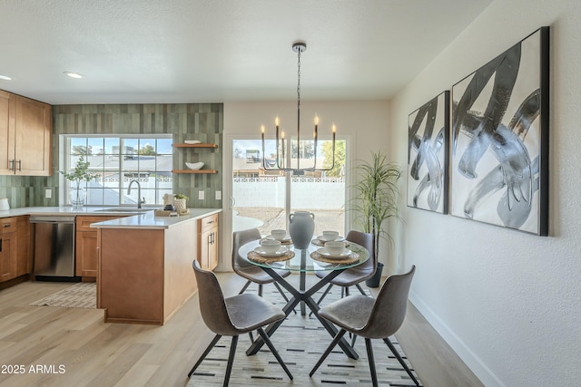 dining area featuring light hardwood / wood-style floors, sink, and a notable chandelier