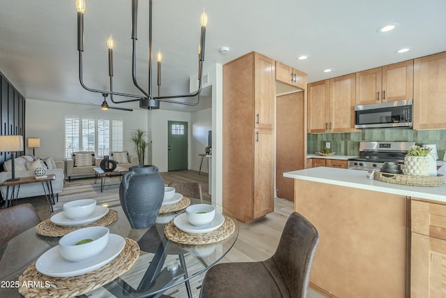 kitchen with pendant lighting, light hardwood / wood-style flooring, ceiling fan, backsplash, and stainless steel appliances