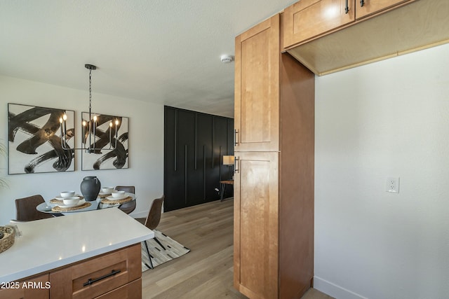 kitchen featuring decorative light fixtures, light hardwood / wood-style floors, a textured ceiling, and a notable chandelier