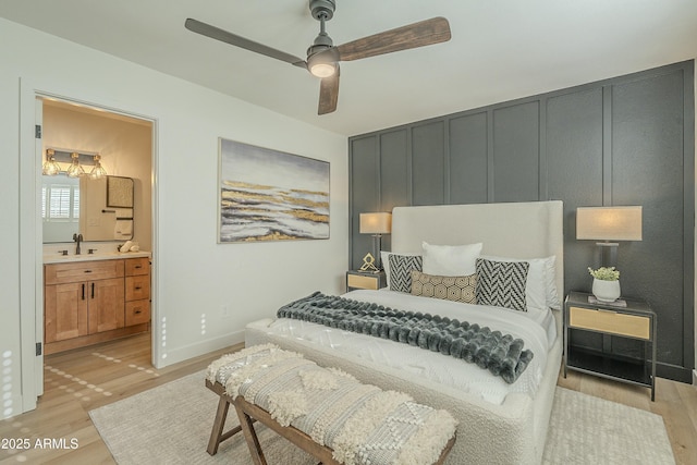 bedroom featuring sink, light wood-type flooring, ceiling fan, and ensuite bathroom