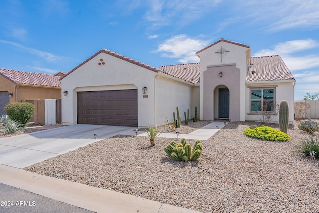 mediterranean / spanish home featuring stucco siding, driveway, an attached garage, and a tiled roof