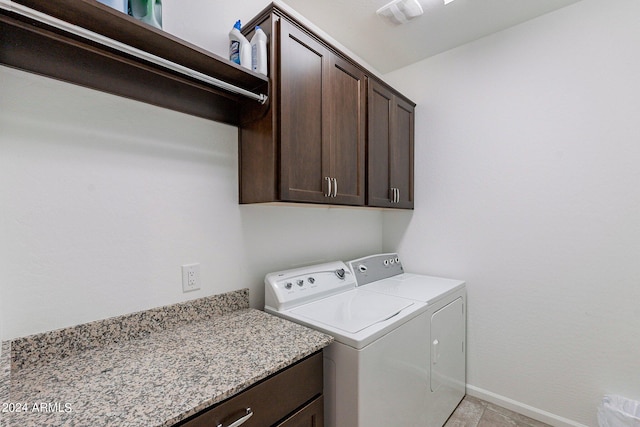 clothes washing area with separate washer and dryer, cabinets, and light tile patterned floors