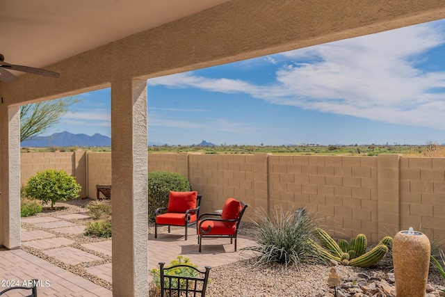 view of patio / terrace with a mountain view, a ceiling fan, and fence