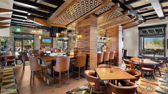 tiled dining space featuring bar, brick wall, and ornate columns