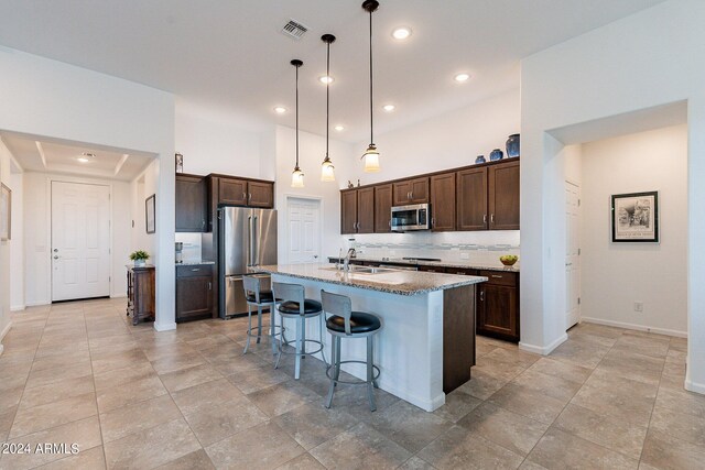 kitchen featuring pendant lighting, a kitchen breakfast bar, sink, an island with sink, and appliances with stainless steel finishes