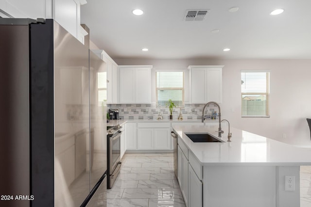 kitchen with marble finish floor, stainless steel appliances, light countertops, decorative backsplash, and a sink