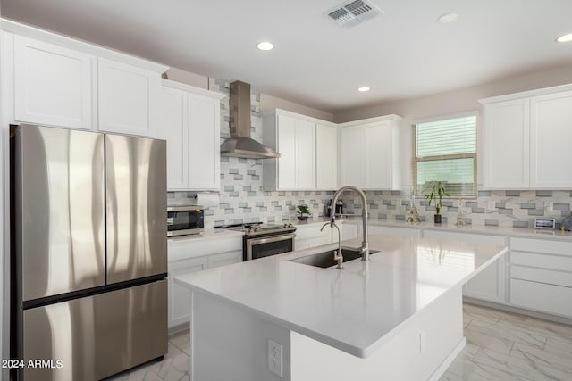 kitchen with light countertops, visible vents, appliances with stainless steel finishes, a sink, and wall chimney range hood