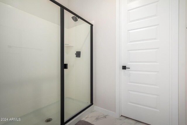 full bath featuring marble finish floor, a shower stall, and baseboards