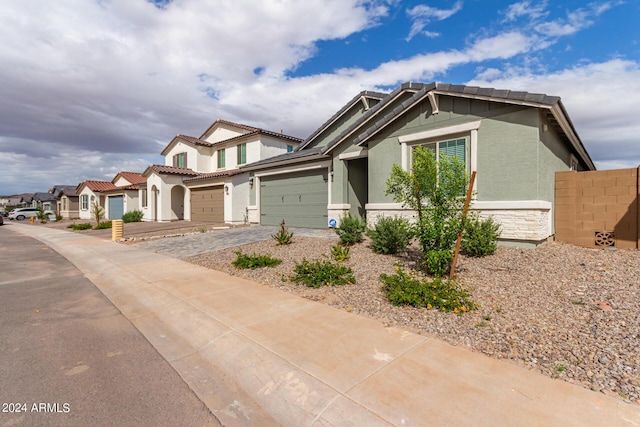 view of front facade with stone siding, driveway, fence, and stucco siding