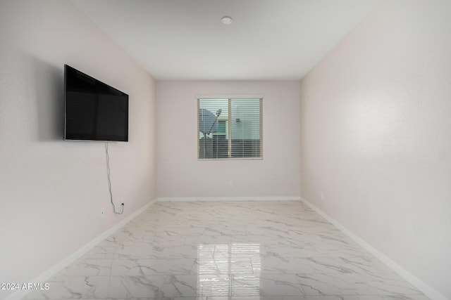 spare room featuring marble finish floor and baseboards