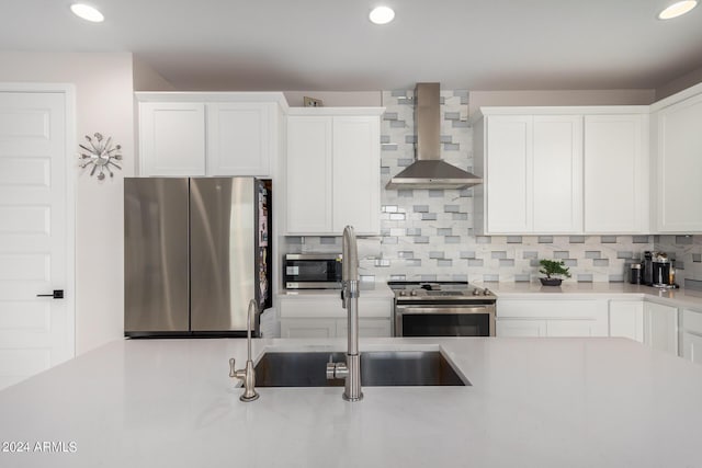 kitchen featuring wall chimney exhaust hood, appliances with stainless steel finishes, a sink, light countertops, and backsplash