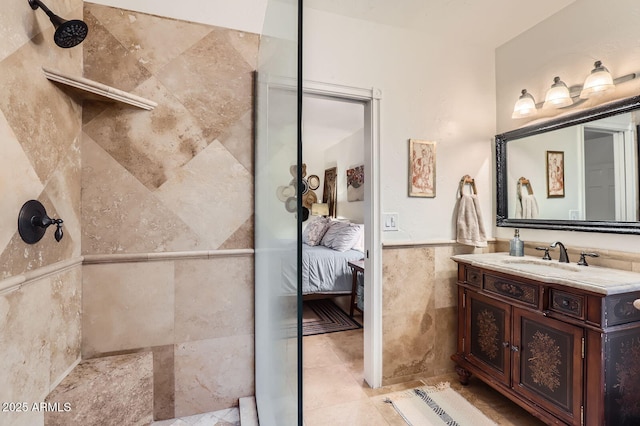 bathroom with vanity, ensuite bathroom, tile walls, and tiled shower