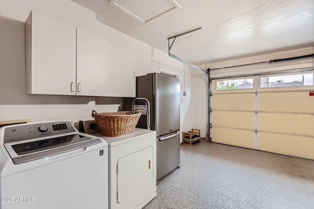 clothes washing area featuring a garage, washing machine and dryer, and cabinet space