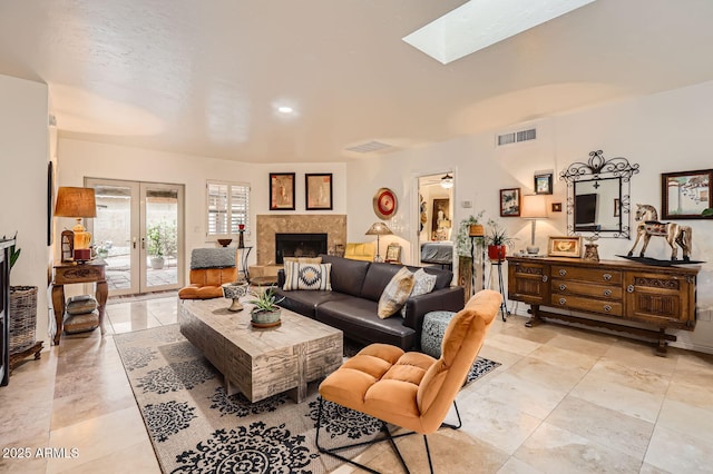 living area with french doors, a fireplace, a skylight, and visible vents