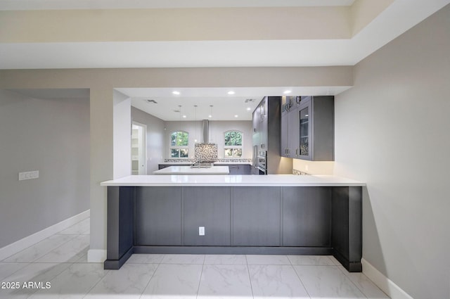 26204 S Washington St, Chandler, AZ 85249 - kitchen with light marble finish floors, wall chimney exhaust hood, glass insert cabinets, light countertops, and a peninsula