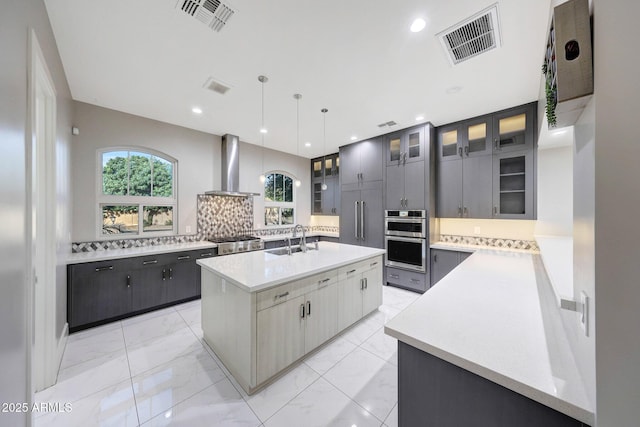 26204 S Washington St, Chandler, AZ 85249 - kitchen featuring exhaust hood, a center island with sink, backsplash, light marble finish floors, and light countertops