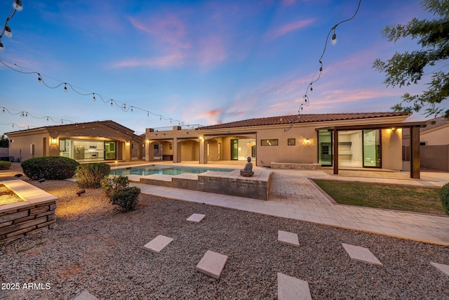 26204 S Washington St, Chandler, AZ 85249 - back of house at dusk with stucco siding, a patio, an outdoor pool, and a tiled roof
