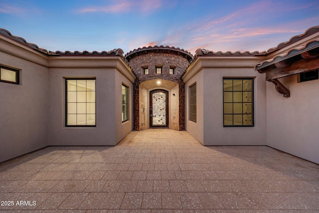 26204 S Washington St, Chandler, AZ 85249 - exterior entry at dusk featuring stucco siding, a patio, and a tile roof